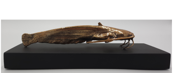 amas_4diving-1.png Handmade Bronze catfish sculpture on a wooden table.